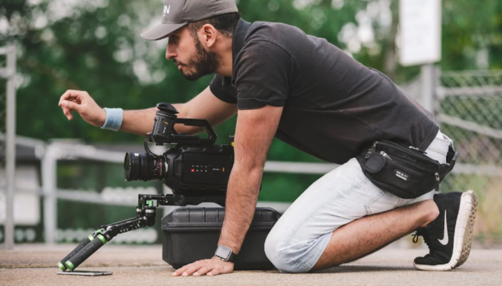 a man kneeling on the ground with a camera